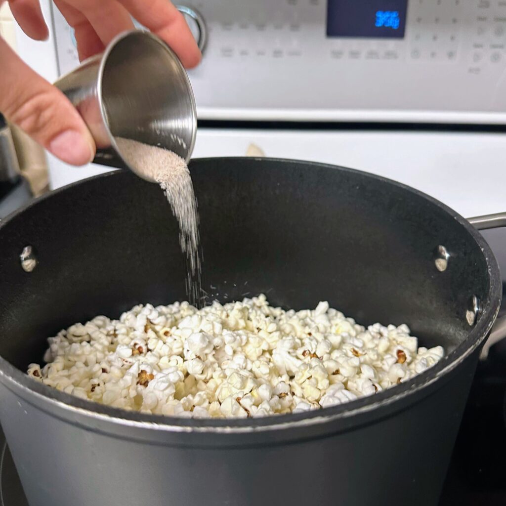 salt pouring into a pot of popcorn